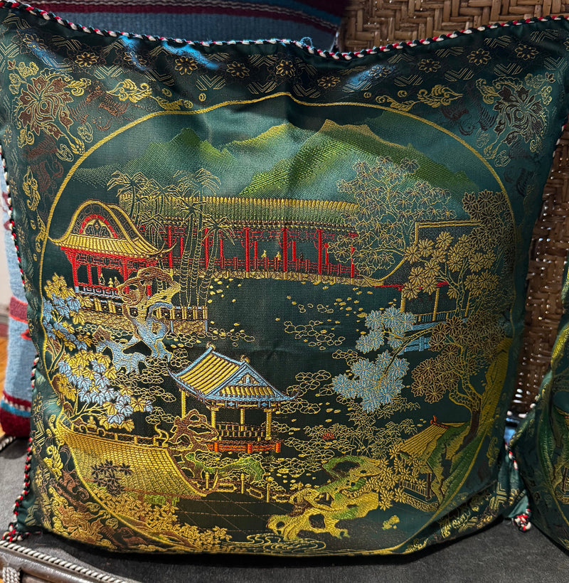 Decorative pillow with a landscape design featuring buildings and trees on a green background.